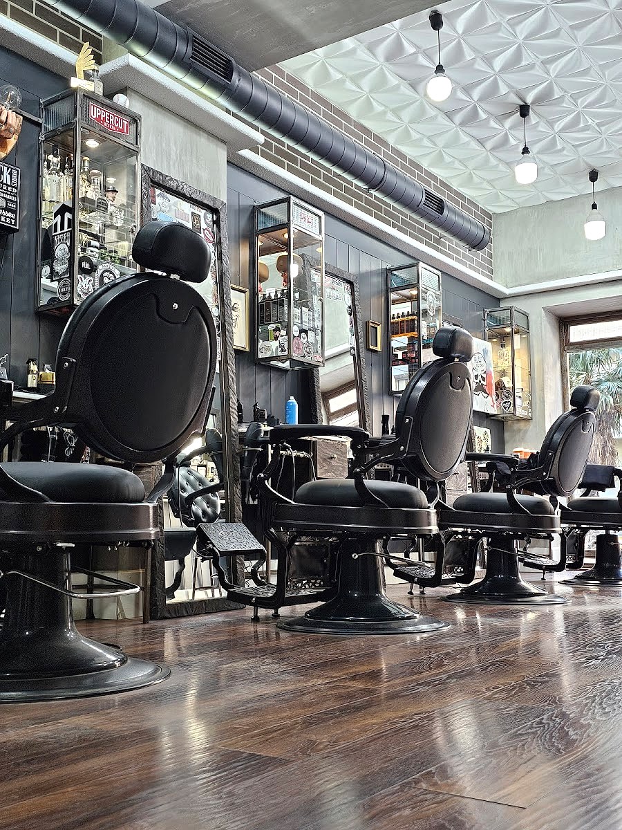 Ο χώρος του Mister No Barber Crew στην Καμάρα, με τις μαύρες οβάλ καρέκλες και τους χρυσούς καθρέφτες